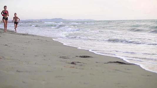 日出时三个孩子在海滩上慢跑Dof慢动作视频的预览图