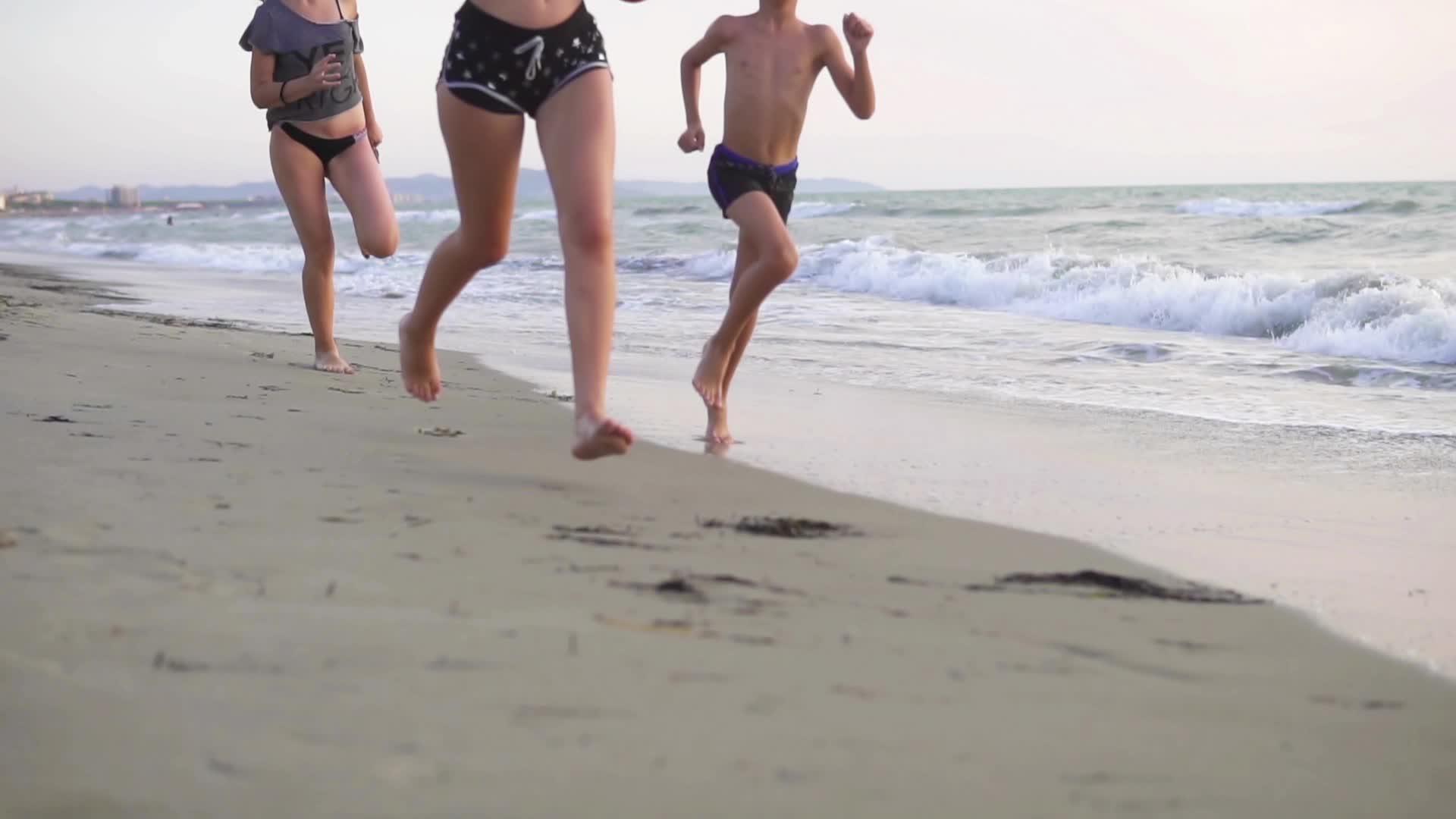 日出时三个孩子在海滩上慢跑Dof视频的预览图