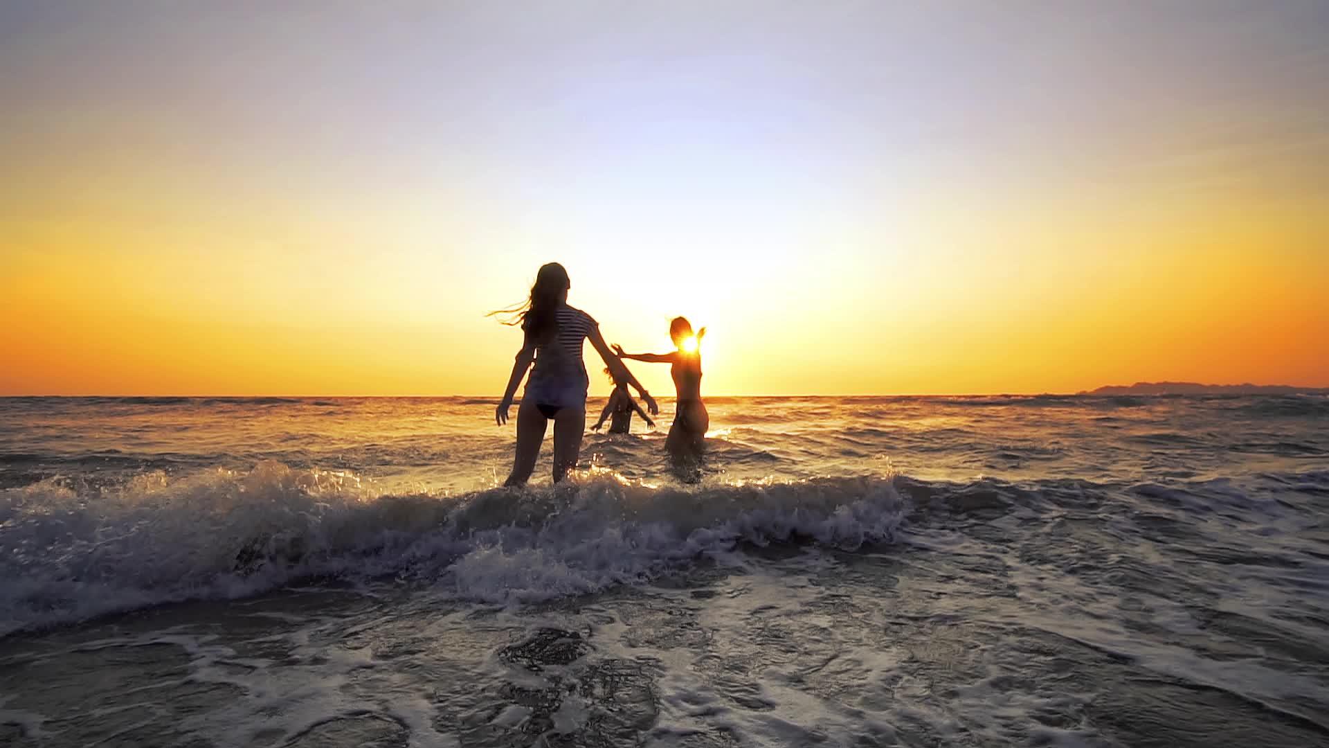 日落时分年轻女性在热带海滩上慢慢地跳舞跳进海洋视频的预览图