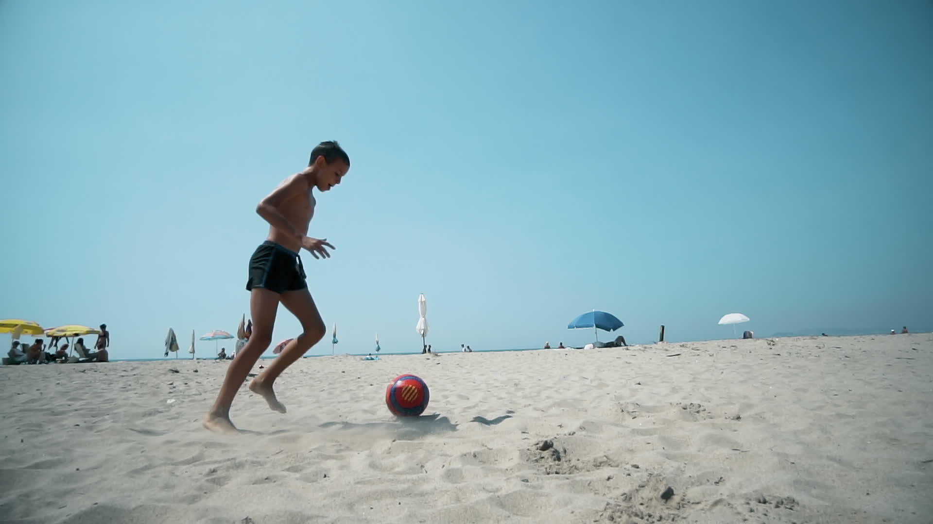 男孩在海滩上慢慢地踢足球视频的预览图