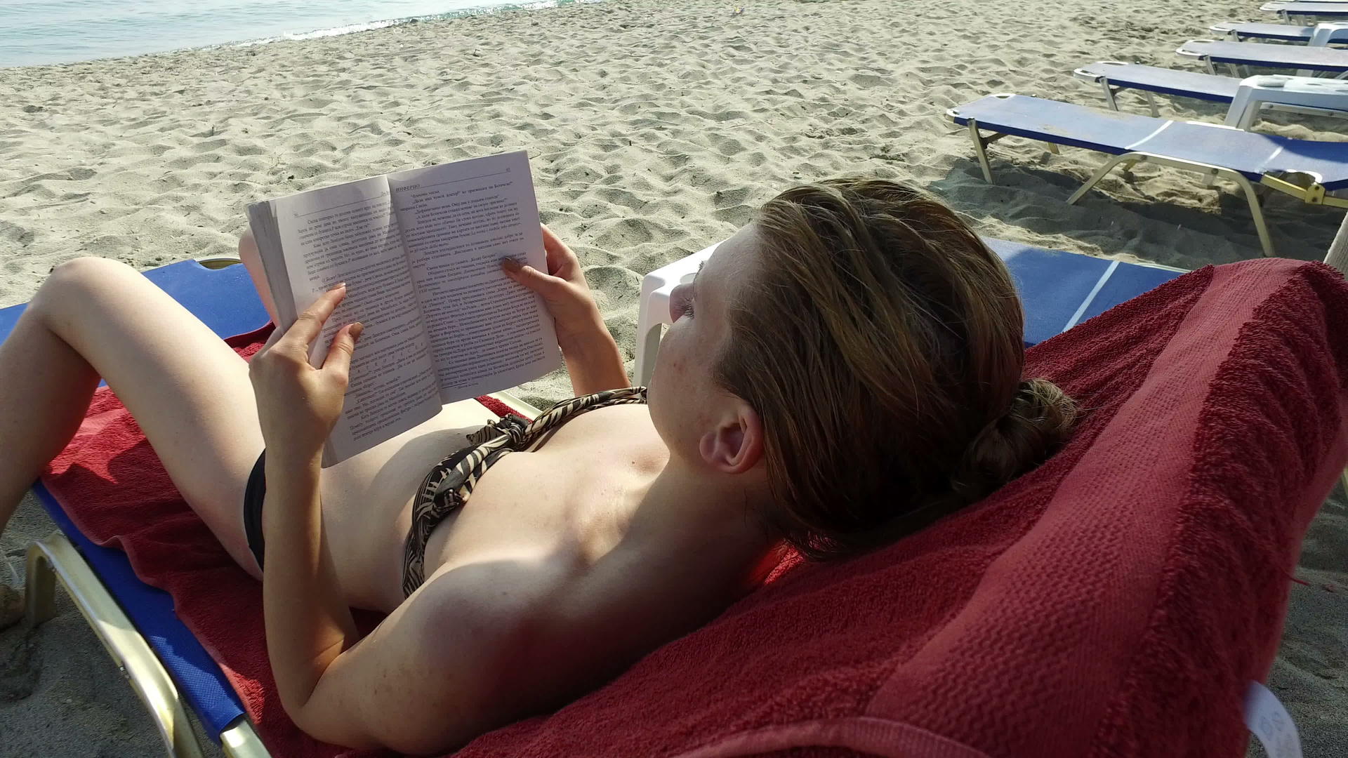 在海滩上看书的青少年稳定摄像机起重4公里射击视频的预览图