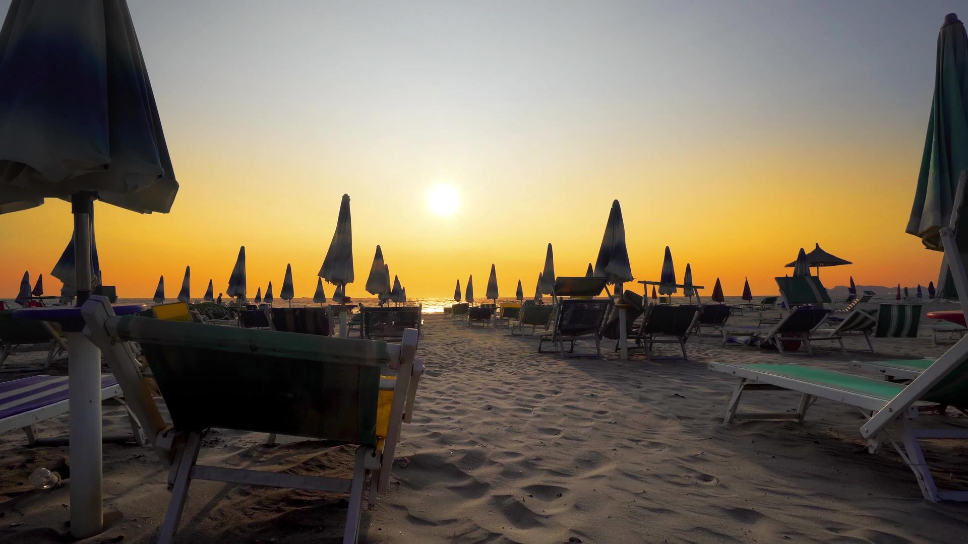 在海滨度假胜地的空海滩上有折叠的太阳休息者和日落天幕视频的预览图