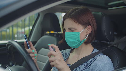 戴口罩的年轻女子坐在车里用手机消毒剂女司机是小工具视频的预览图