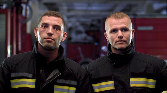 两名消防队员穿着制服和黄色保护头盔站在一起近距离肖像视频的预览图