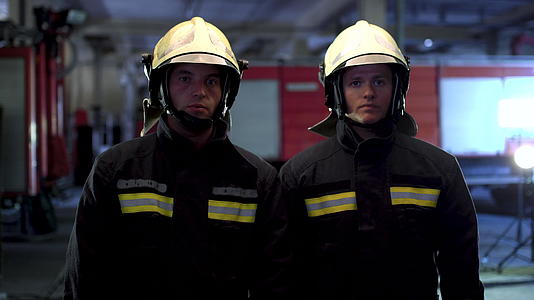 两名消防员穿着制服和防护头盔站在一起视频的预览图