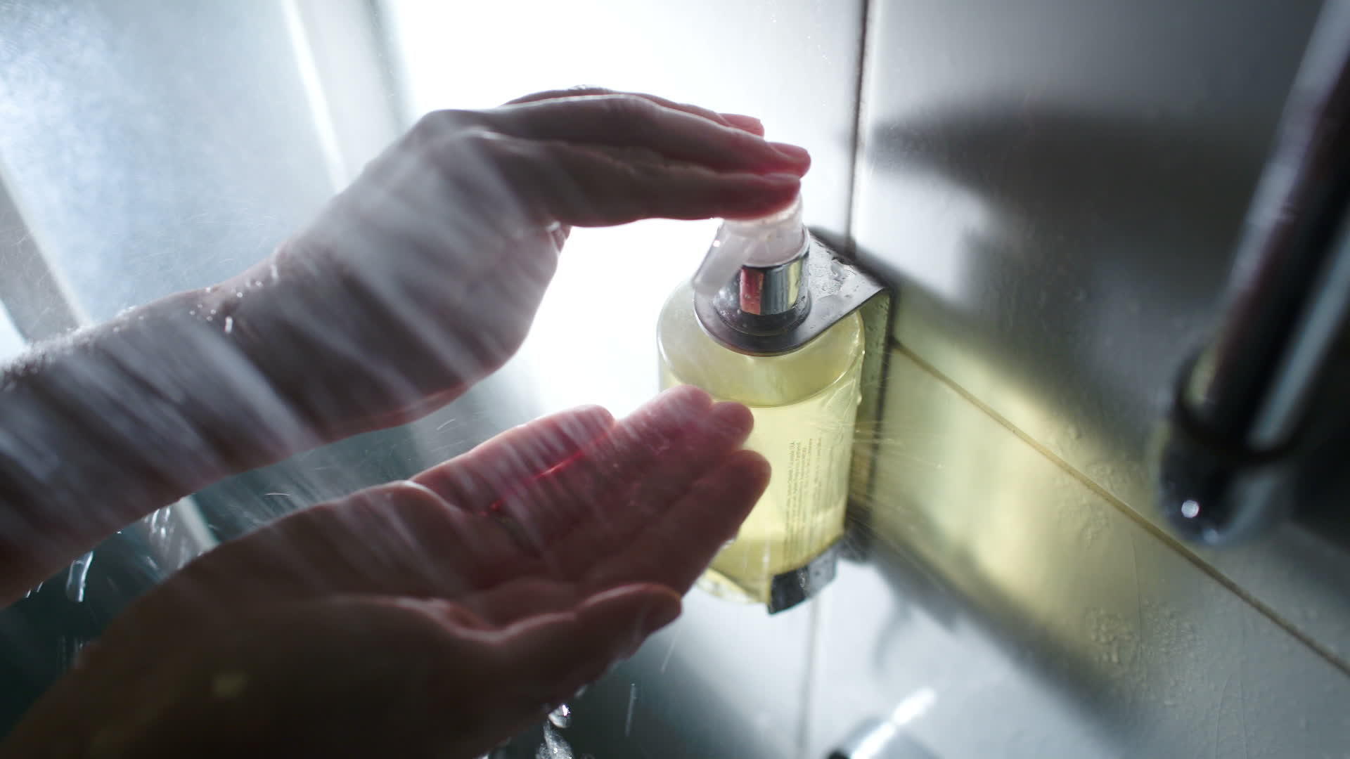 女性在淋浴时用液化肥皂将容器推到女性手上视频的预览图