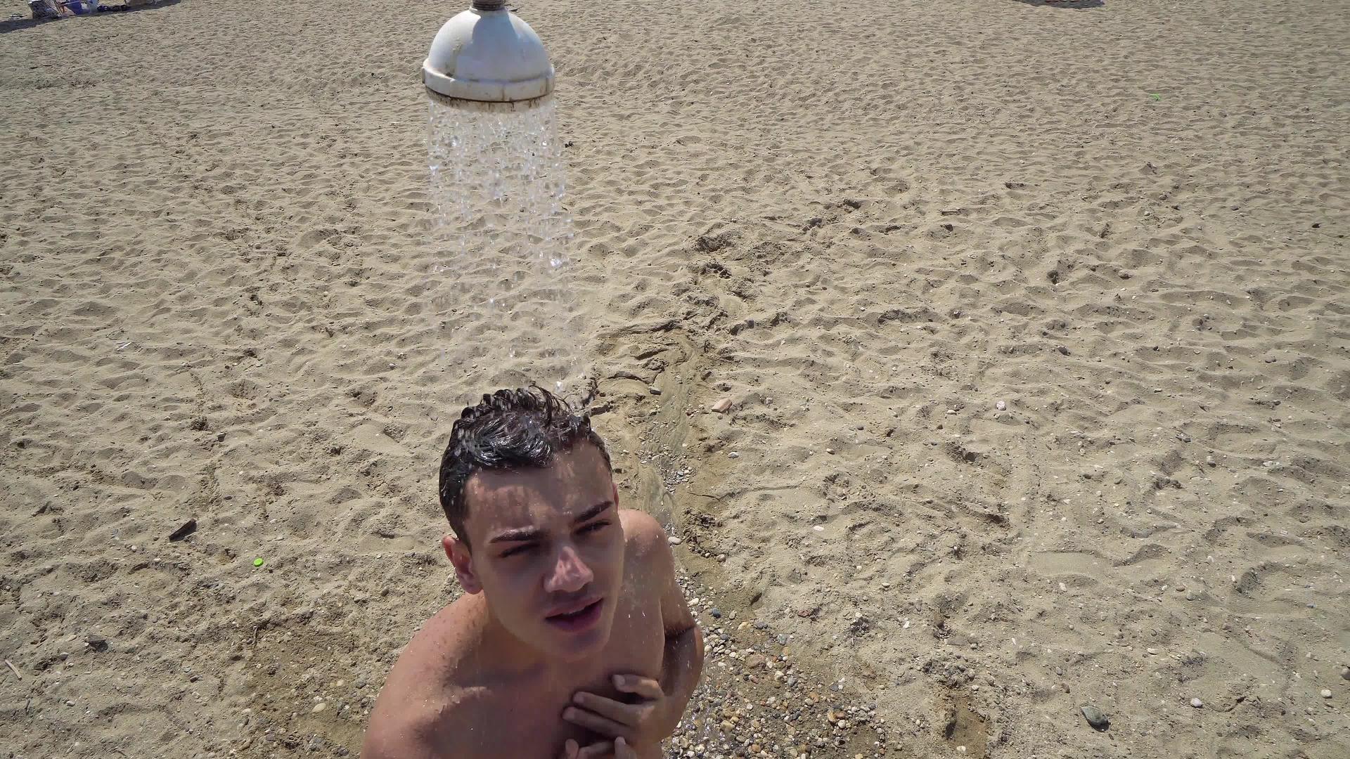 年轻男子在海滩淋浴中洗头视频的预览图