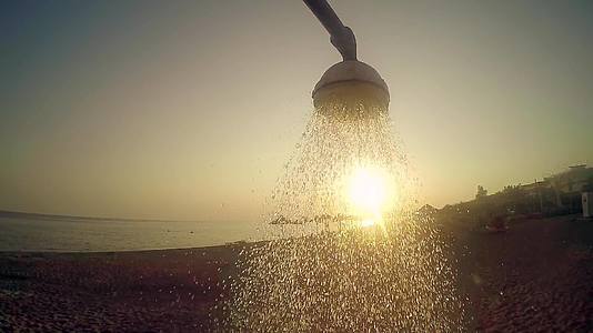 夏季概念慢动作沙滩头浴用自来水对抗日落太阳视频的预览图