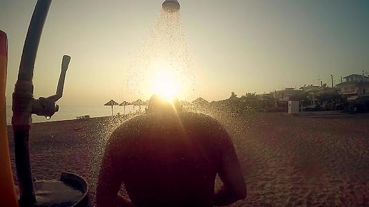 这名男子在海滩上露天洗澡在日落和的光线下慢慢移动视频的预览图