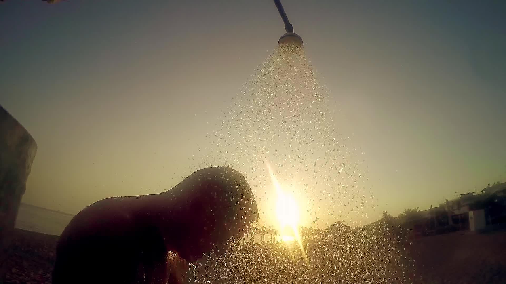这名男子在海滩上露天洗澡在日落和的光线下慢慢移动视频的预览图