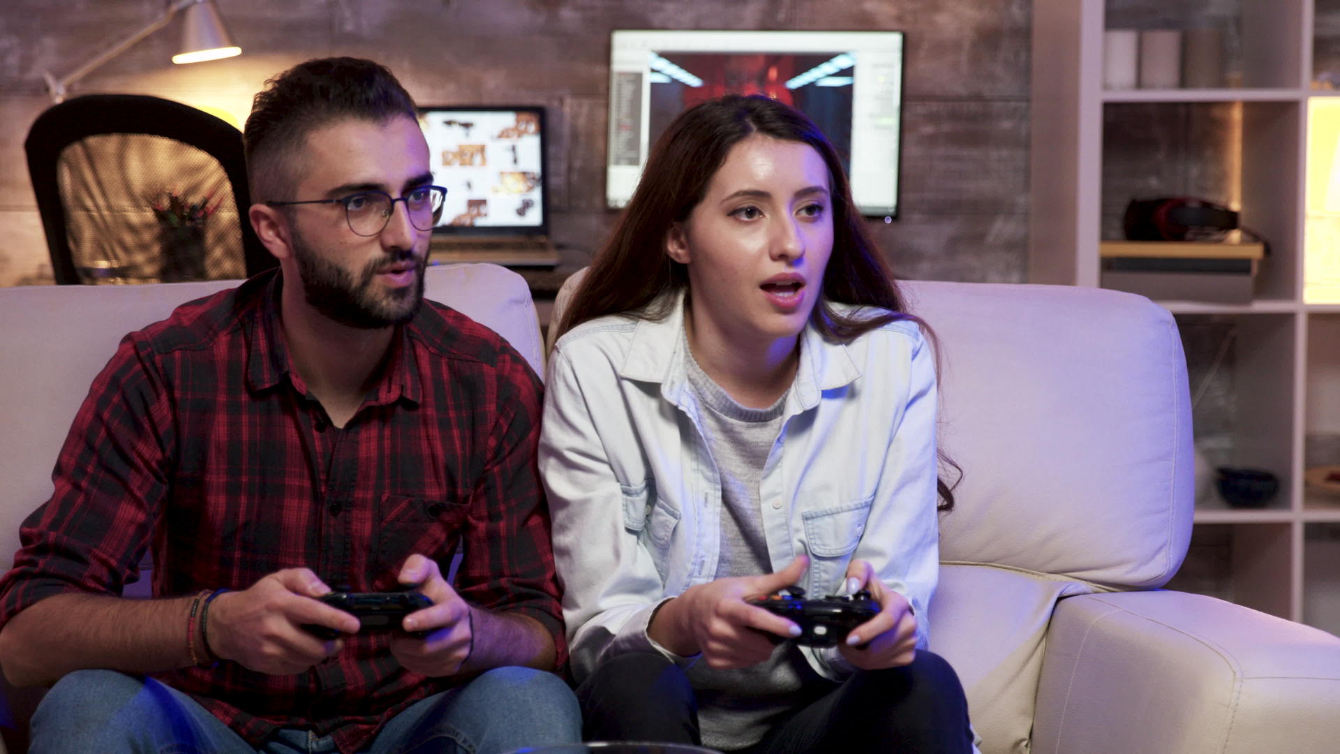 一对夫妇坐在沙发上放松玩电子游戏视频的预览图