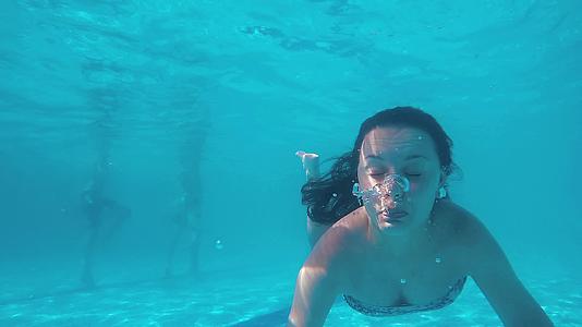 青少年在水下游泳在游泳池里制造气泡在恐慌中慢慢移动视频的预览图