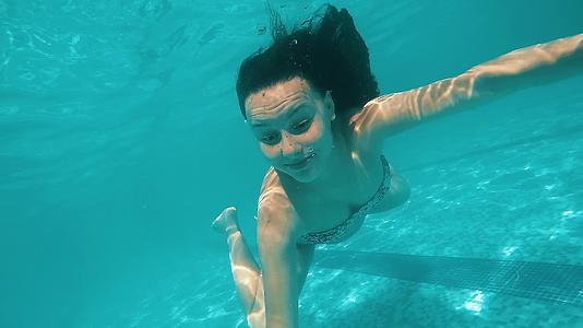女孩在游泳池的恐慌中淹没了寒冷的水在水下慢慢移动视频的预览图