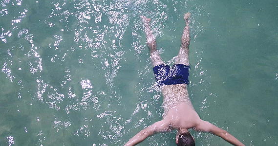 空中无人驾驶飞机射杀海中溺水的男子绿色的石头清澈的海水视频的预览图