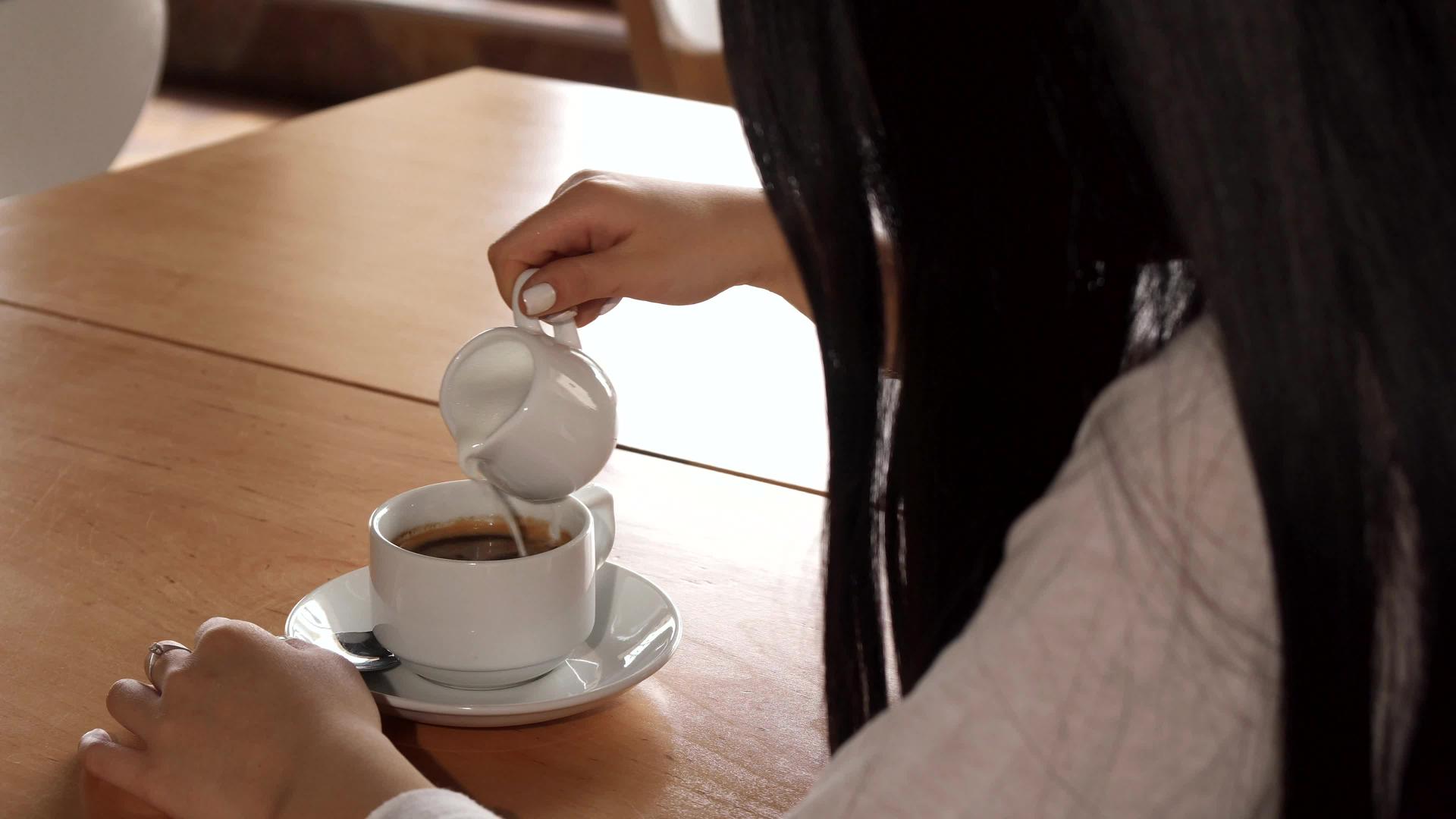 女孩在咖啡馆的咖啡中加入奶油视频的预览图