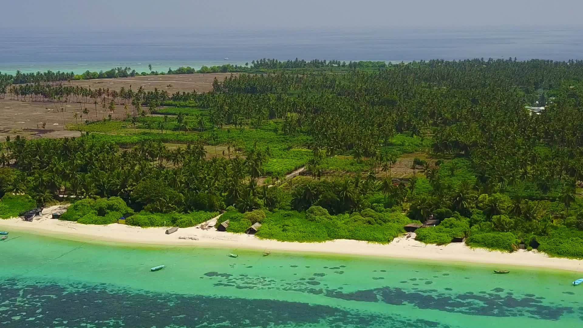通过蓝绿色的海洋和白沙底蓝海环礁湖海滩靠近度假胜地视频的预览图