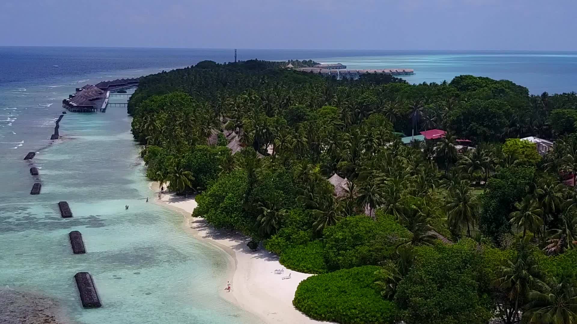 穿过蓝绿色的环礁湖和靠近珊瑚礁的白色沙底背景视频的预览图