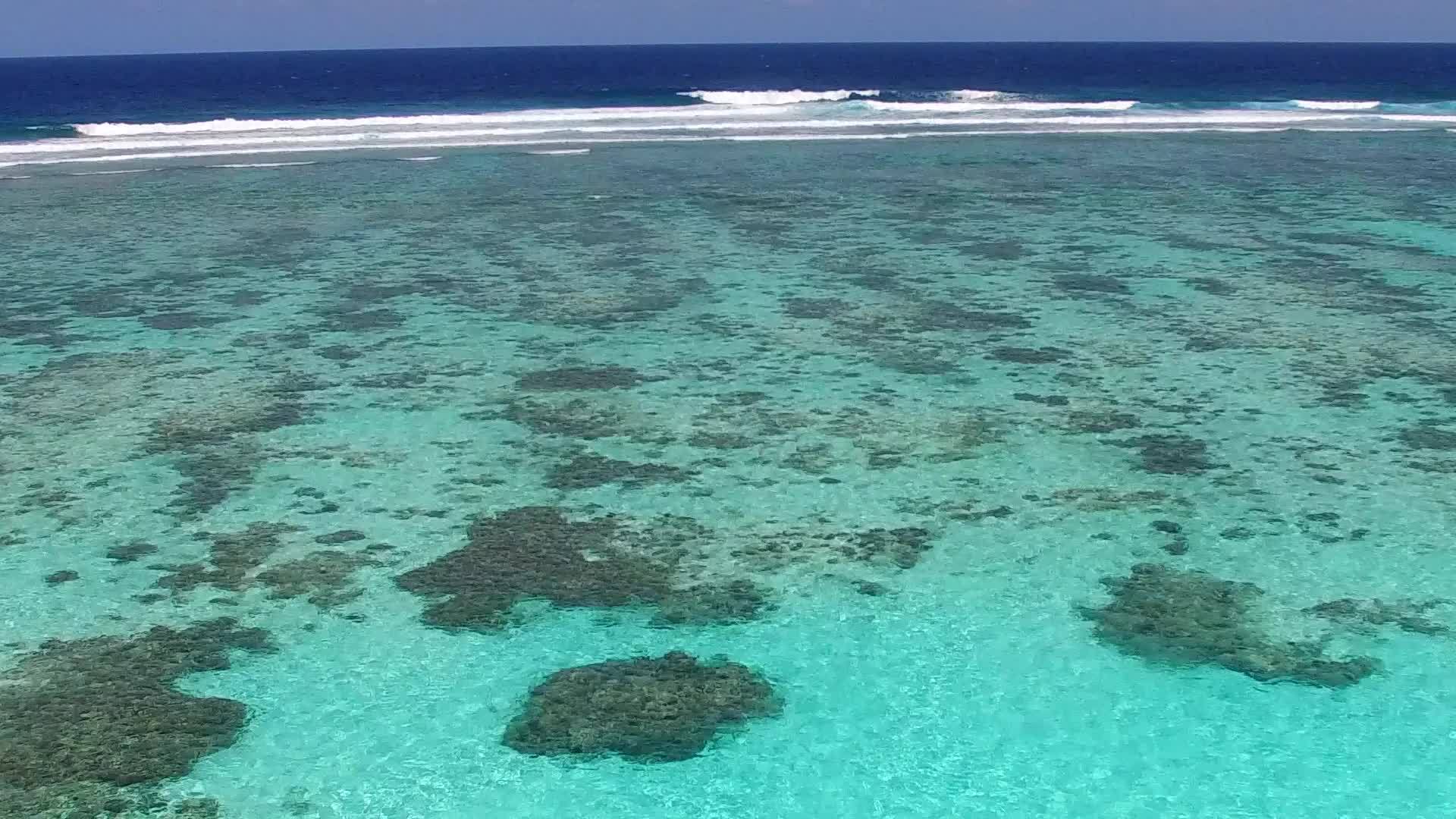 海滨海滩时间宽角天空蓝海和珊瑚礁附近的白沙背景视频的预览图