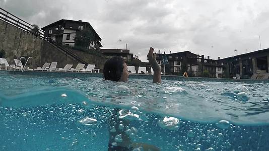 年轻女子在热温泉游泳池里清新用温泉水的泡泡喷出相机视频的预览图
