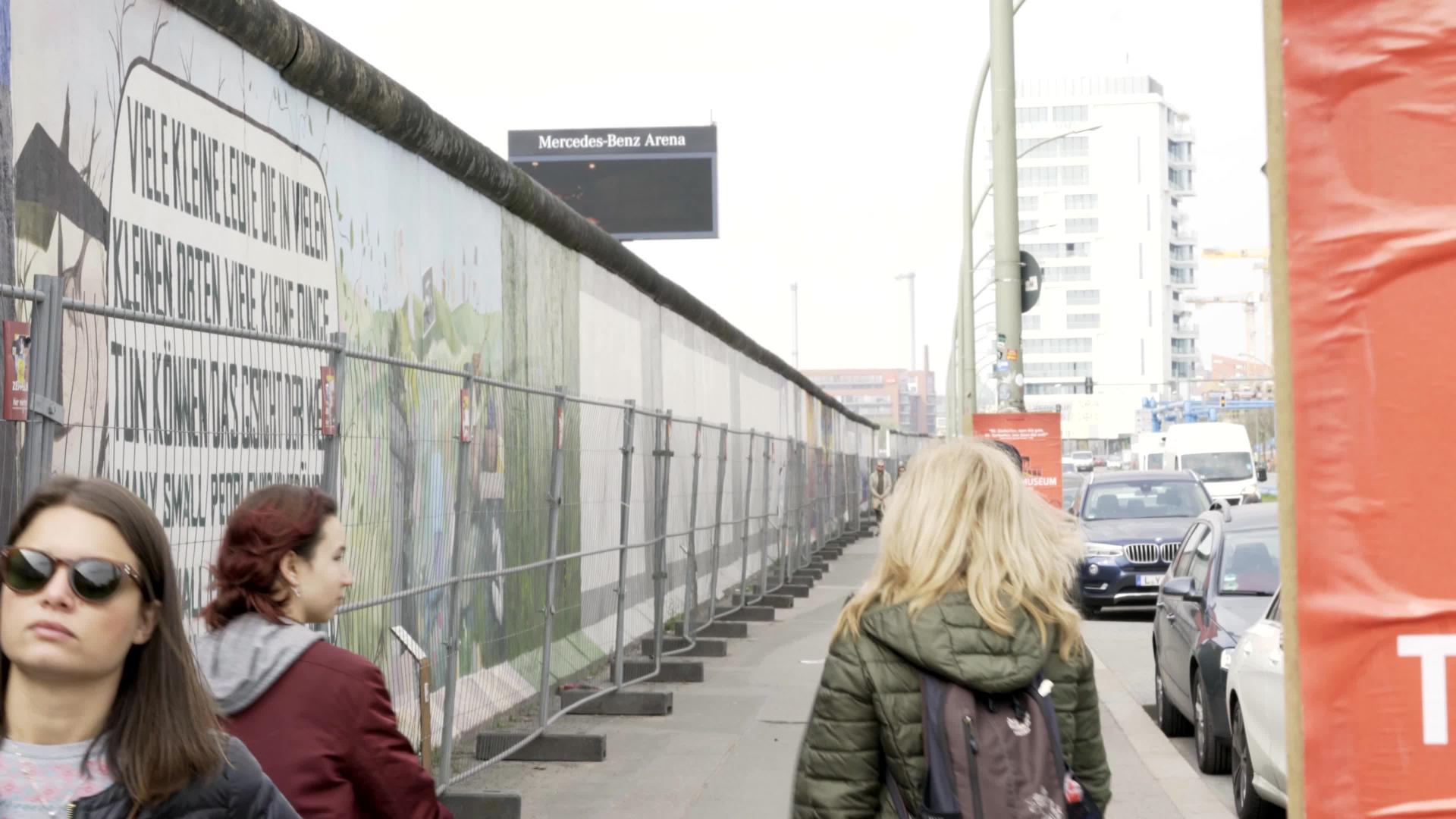 游客穿过柏林东部的画廊墙壁上布满了绘画视频的预览图