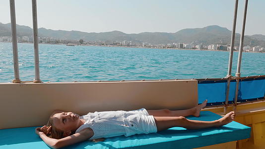 旅行女孩在海上漂浮的游艇上放松年轻的女孩躺在帆船上视频的预览图