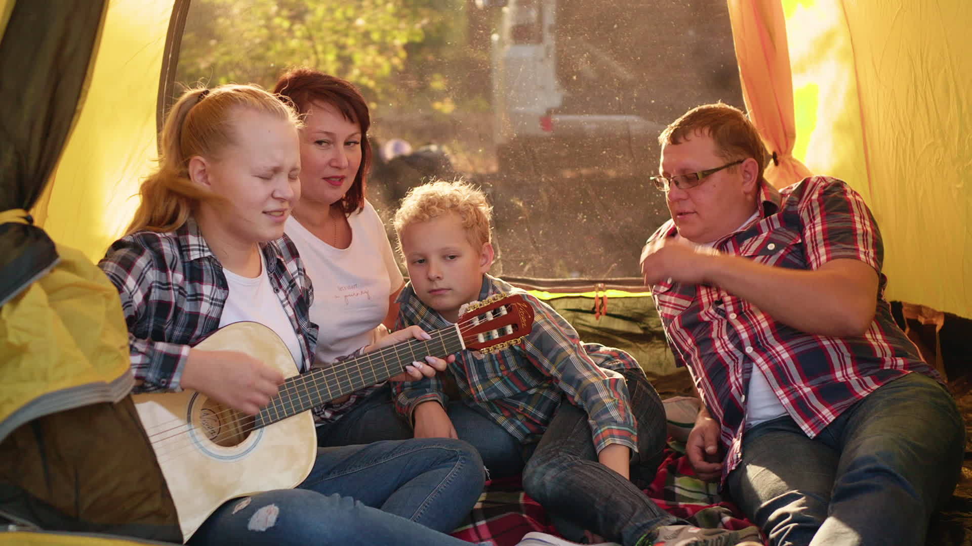 旅游家庭在森林徒步旅行的露营帐篷里用吉他唱歌视频的预览图