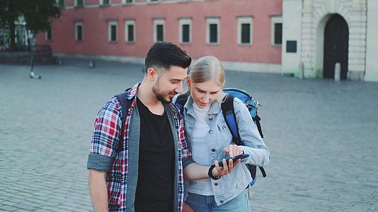 快乐的游客带着智能手机在欧洲老城区的市中心寻找美丽的东西视频的预览图
