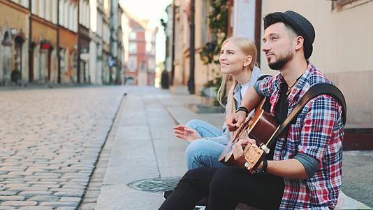 游客坐在人行道上弹吉他和休息视频的预览图