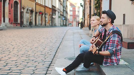 游客坐在人行道上弹吉他和休息视频的预览图