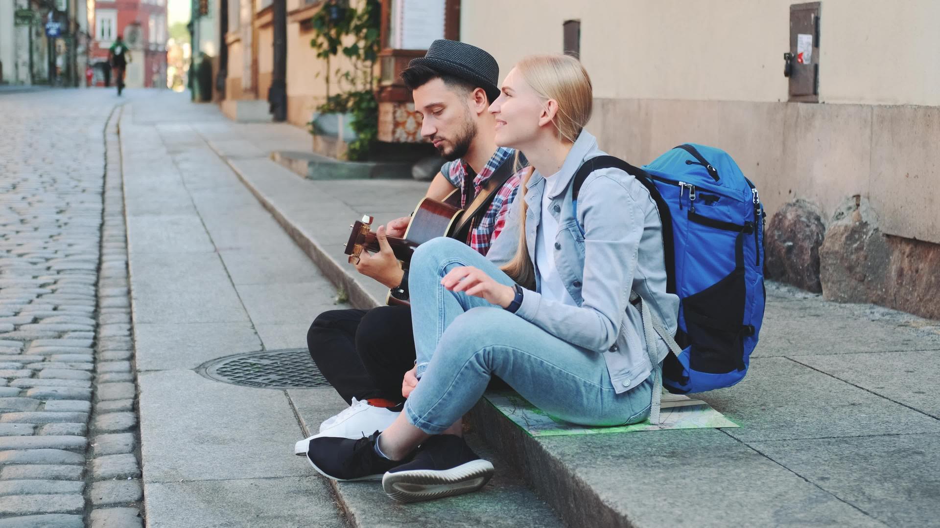 几对游客坐在人行道上弹吉他和休息视频的预览图