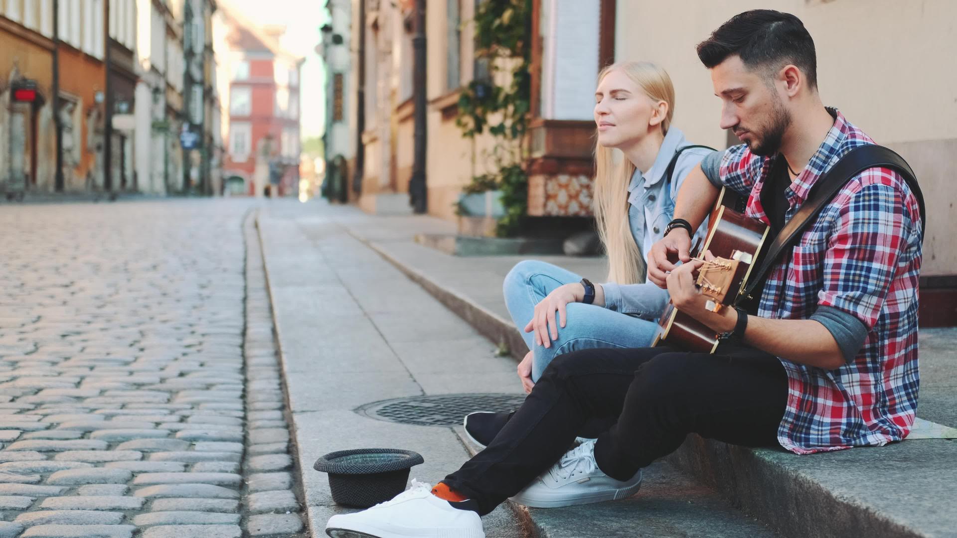 年轻男女在人行道上弹吉他和唱歌的街头歌手中视频的预览图