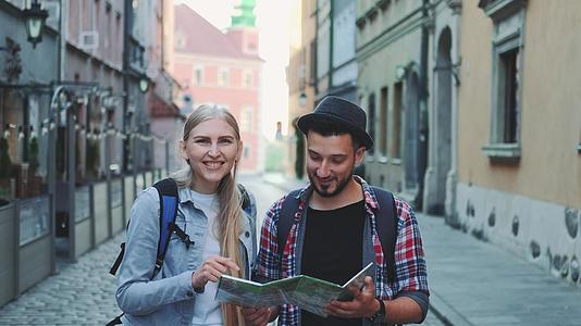 两名年轻游客在主要旅游街上行走时检查地图视频的预览图