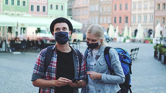 佩戴保护性口罩和使用智能手机袋的年轻游客视频的预览图