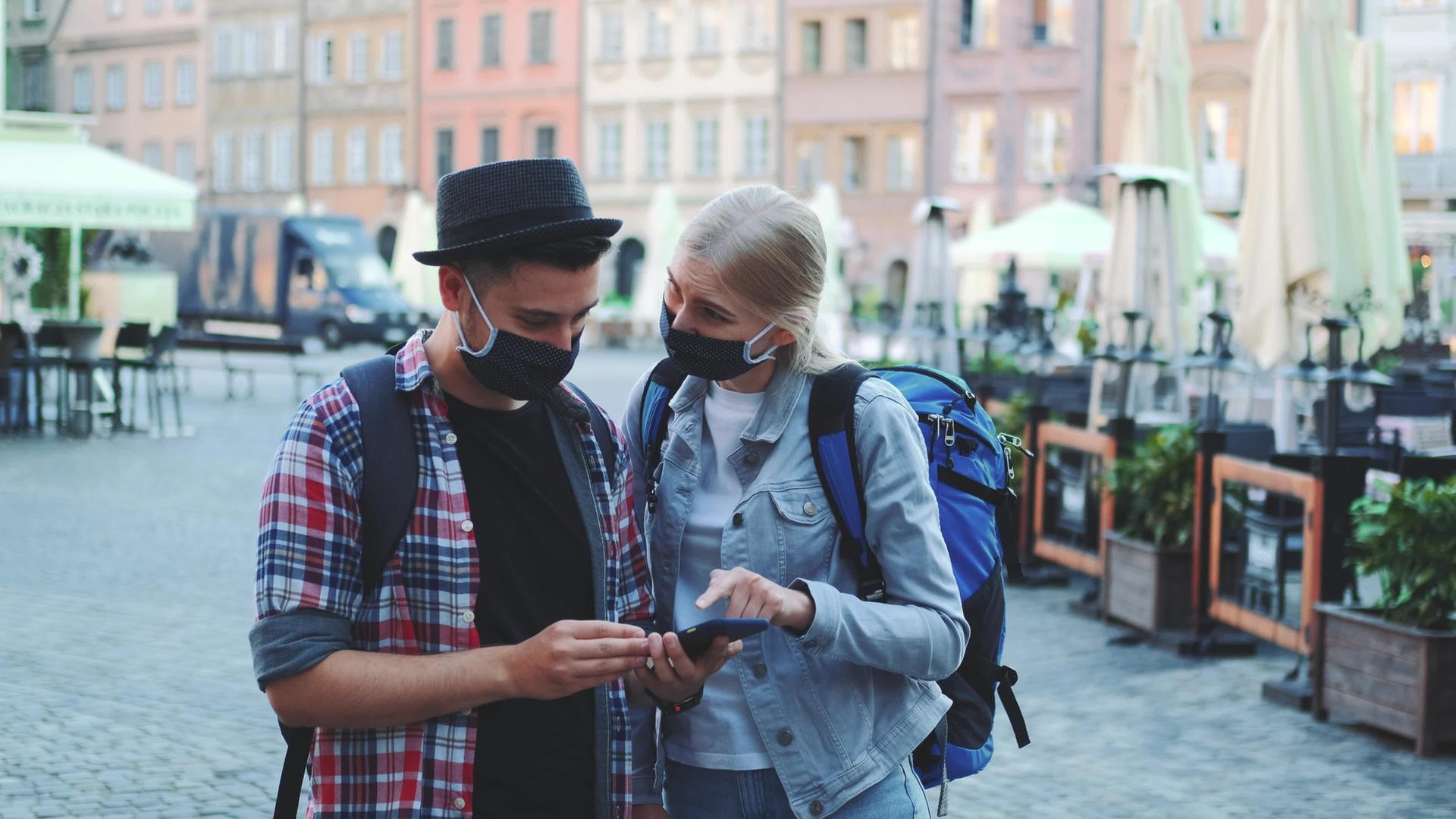 男女戴防护口罩使用智能手机袋视频的预览图