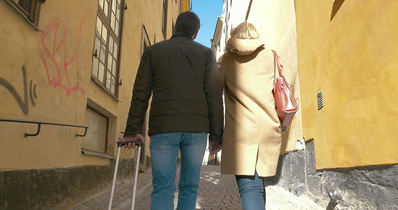 两对带着滚袋的游客走在老街上视频的预览图