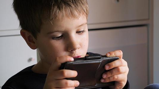 男孩在智能手机上玩手机游戏学龄前儿童玩手机孩子们用手机视频的预览图