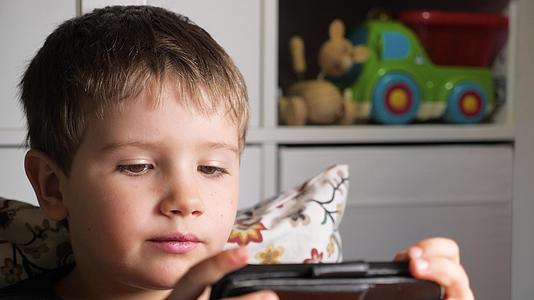 孩子们在智能手机上玩手机游戏男孩在家里用手机玩游戏视频的预览图