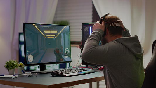 网络运动游戏玩家戴着耳机玩第一人射击游戏视频的预览图