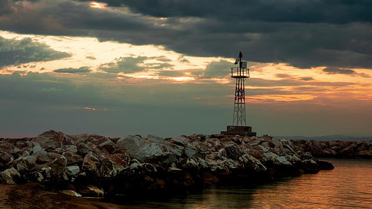 日落时刻悬浮在岩石海岸的灯塔上视频的预览图