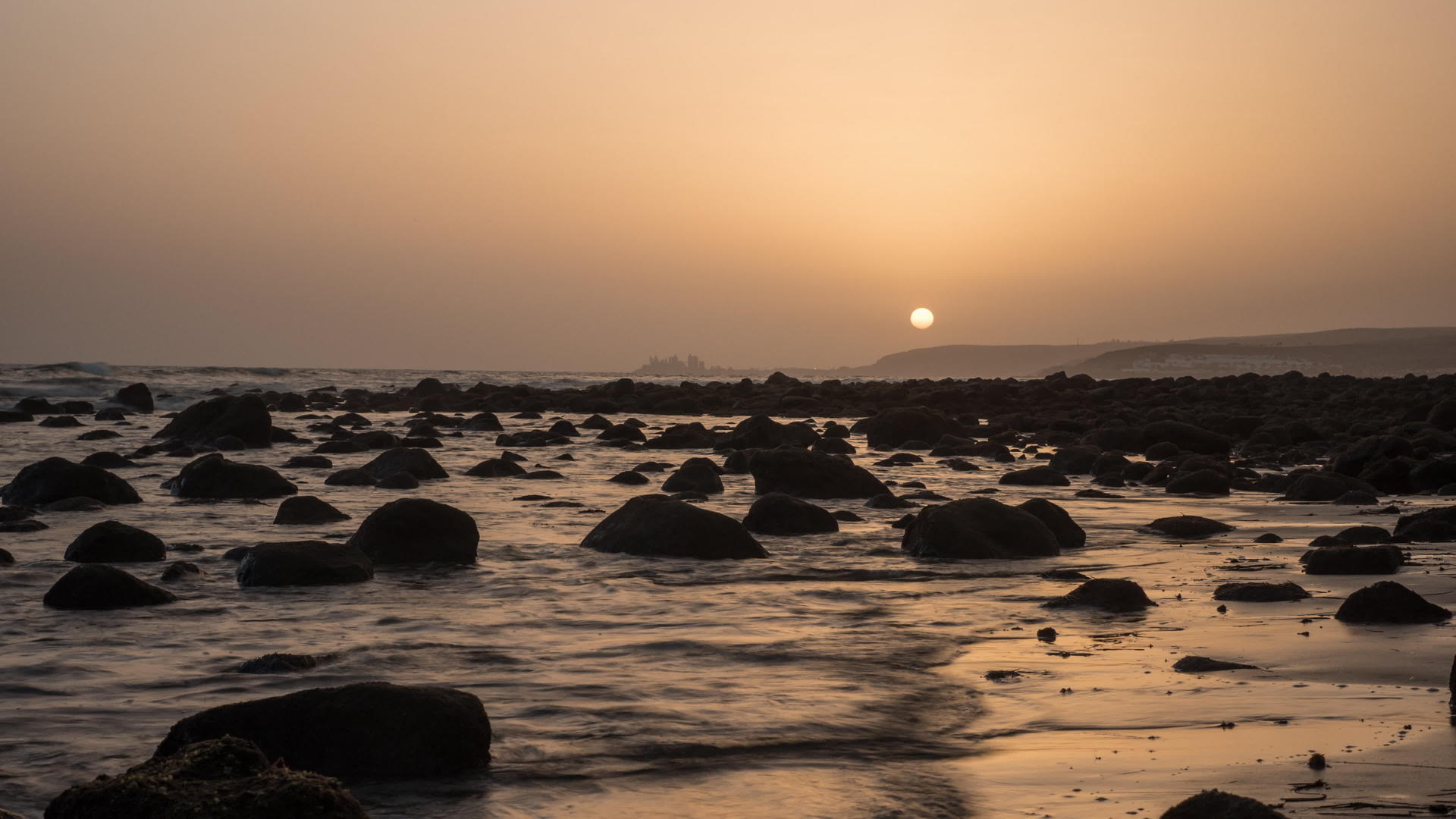 海浪在海岸上伴随着日落时的岩石视频的预览图