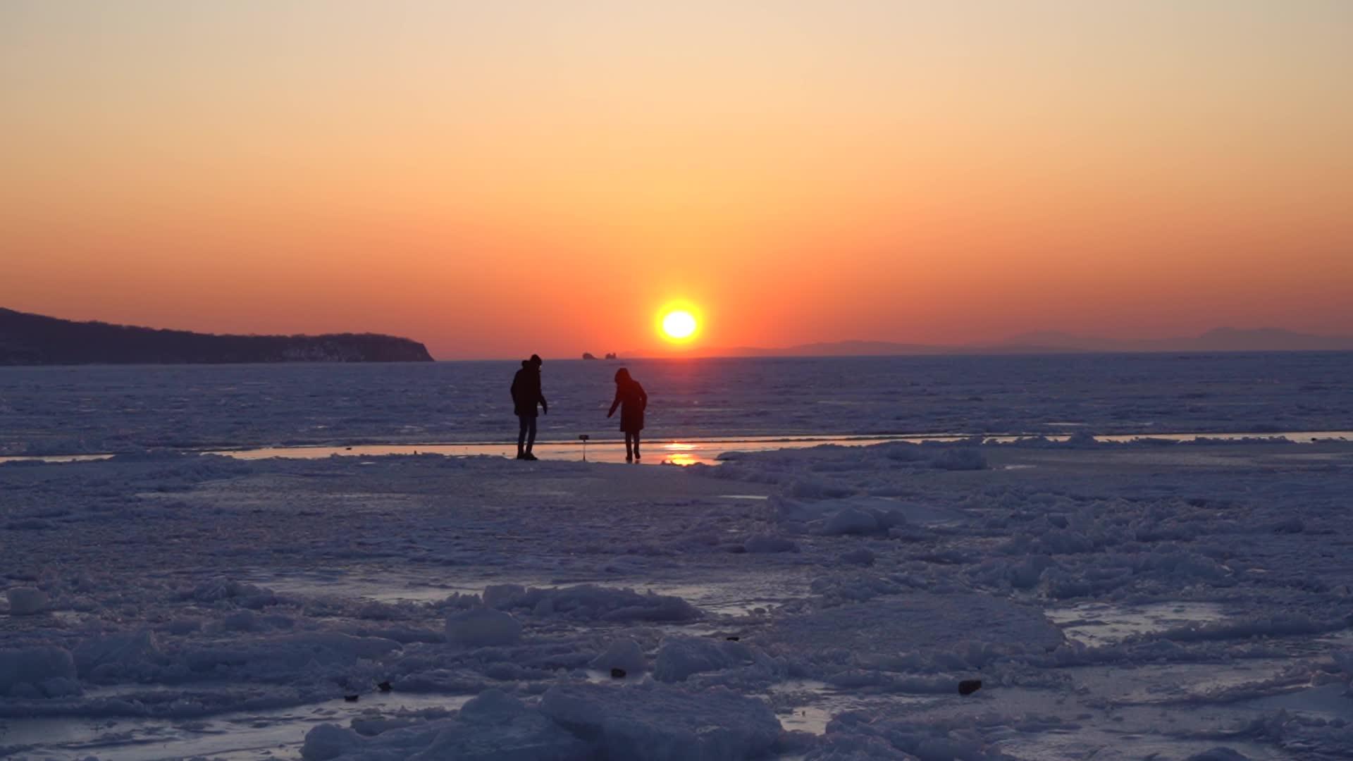 一个男人和一个女孩在海洋冰雪表面的日落时间视频的预览图