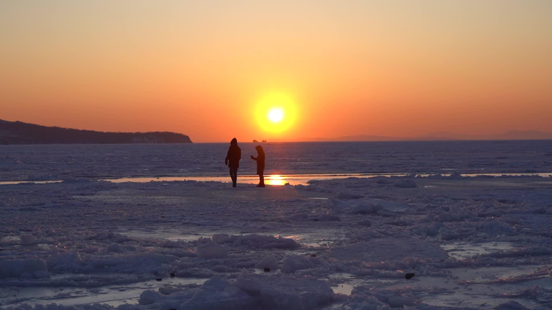 一个男人和一个女孩在海洋冰雪表面的日落时间视频的预览图