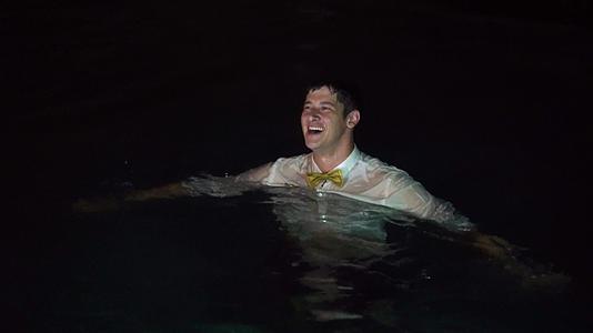 一个年轻人在游泳池里穿着衬衫和其他衣服洗澡晚上在热带地区洗澡视频的预览图
