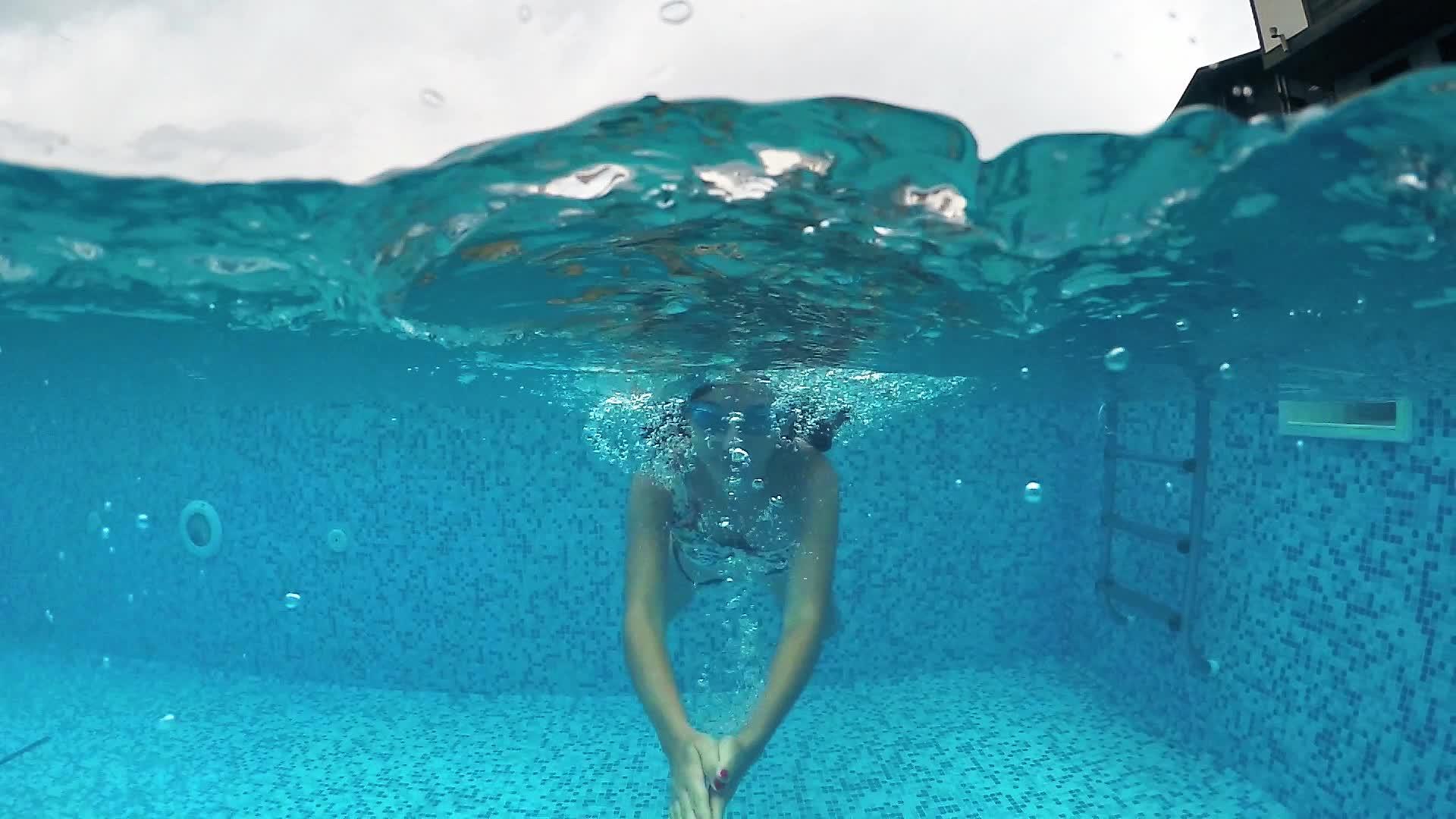 一个快乐的年轻女子带着谷歌潜入游泳池视频的预览图