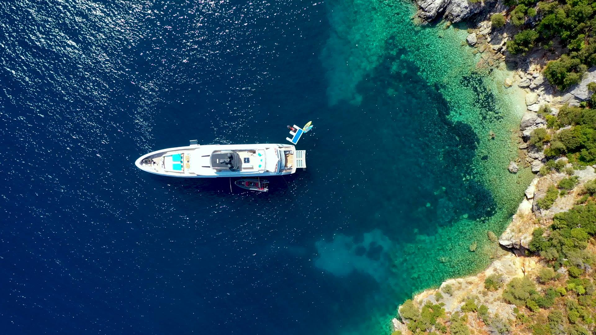 游艇停泊在热带岛屿前面的水晶般清澈的绿松石水中视频的预览图