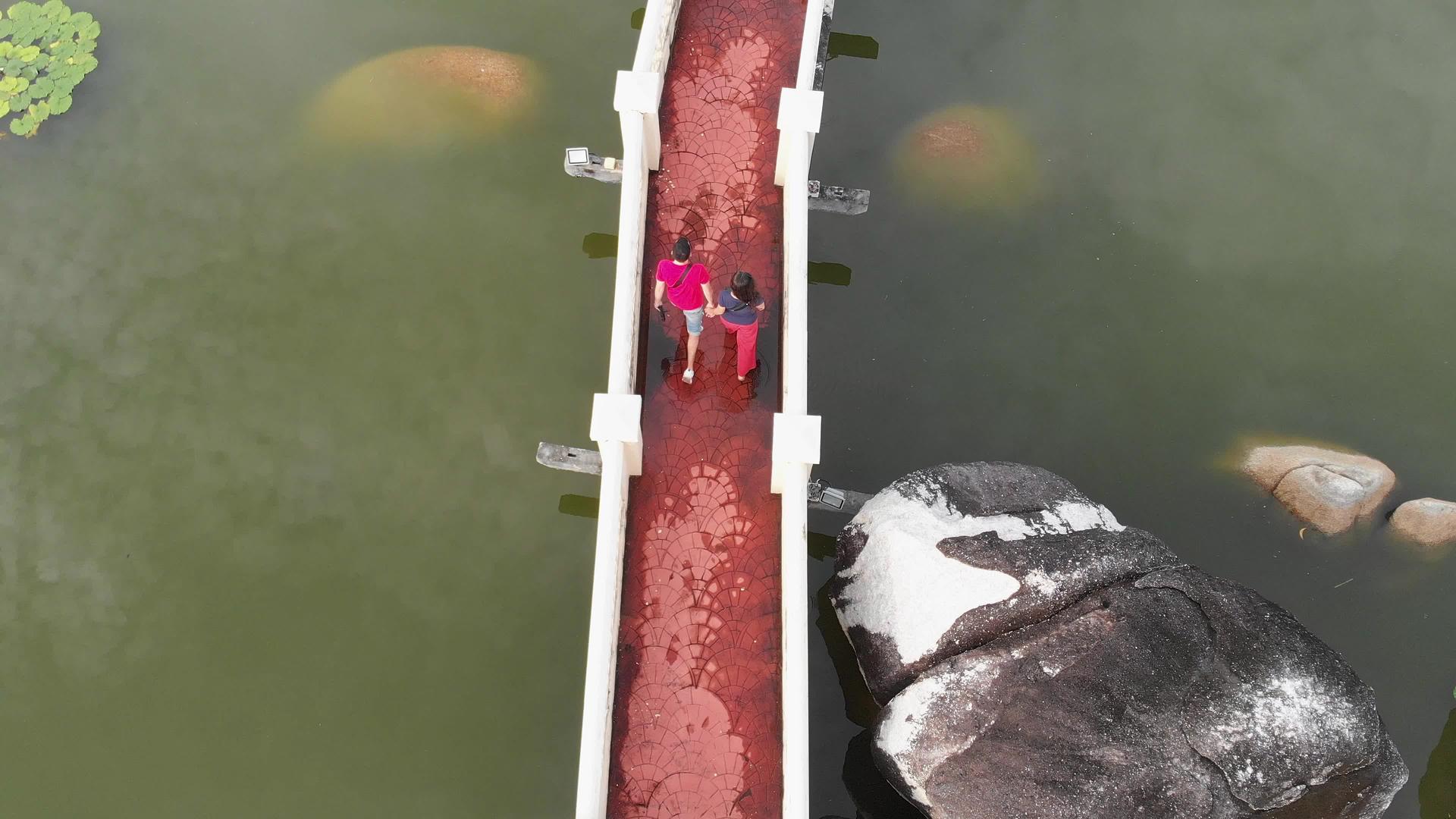 一个男人和一个女孩走过公园对面的桥视频的预览图