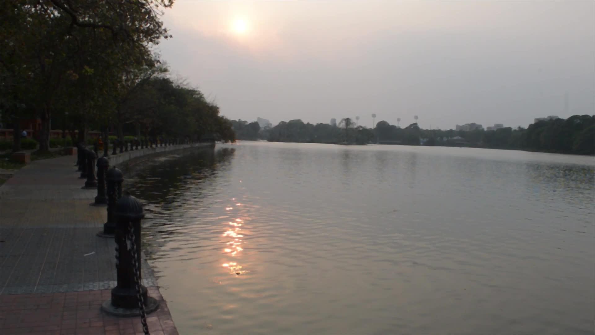 夏天的傍晚湖滨公园的夕阳照亮了花园小径公园的车道风景视频的预览图
