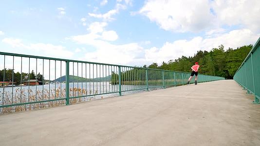 直排轮滑运动员穿着红色T恤和黑色裤子在桥上滑冰视频的预览图