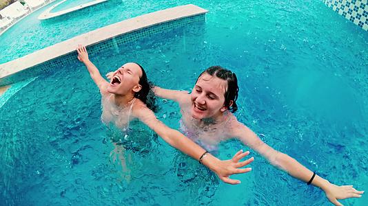 暑假期间在游泳池里女孩们在雨中微笑和大笑下雨了水滴落在雨中视频的预览图
