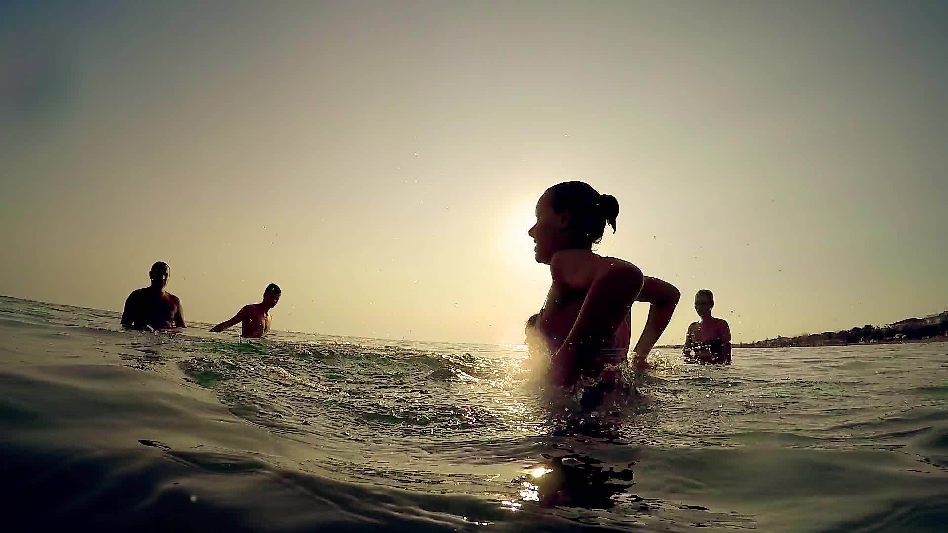一群朋友在日落时在海里玩湿喷水慢动作视频的预览图
